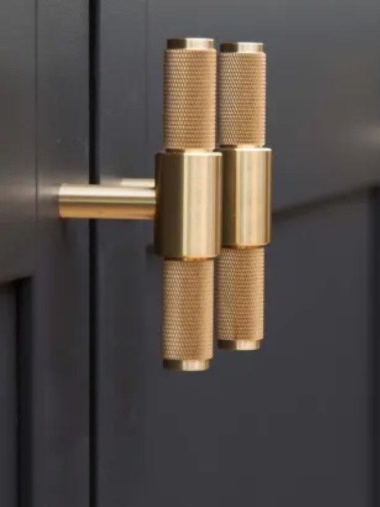 Close-up of brushed brass Buster + Punch cabinet handles mounted on dark shaker-style kitchen doors