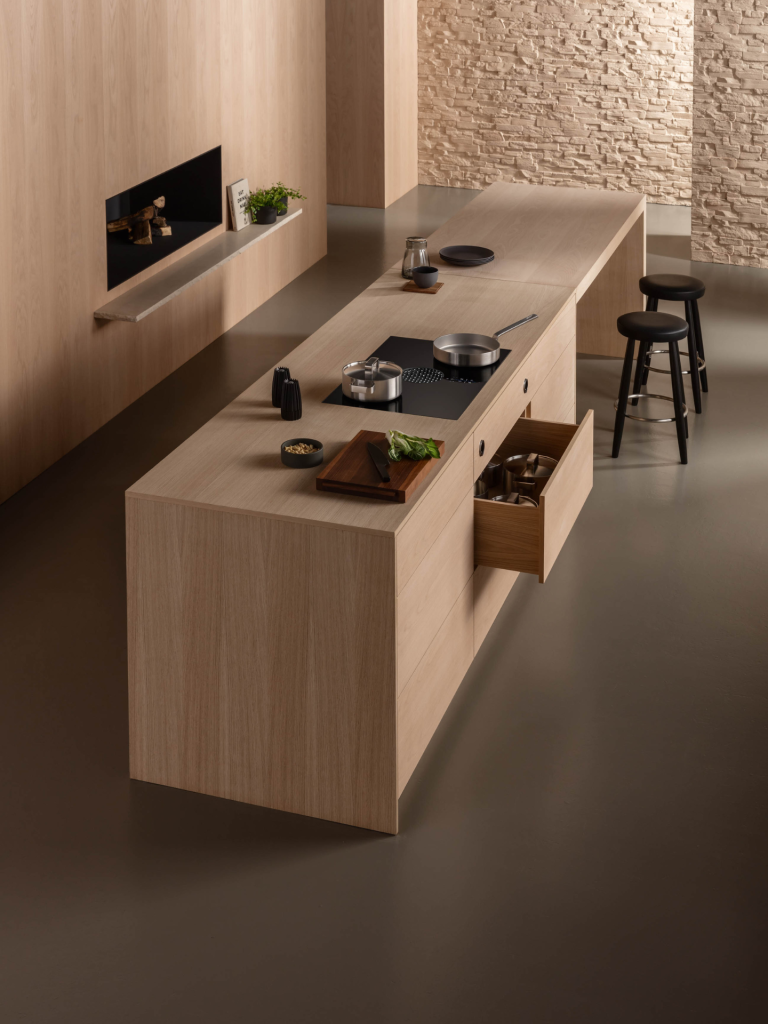 Modern minimalist kitchen with light oak island featuring a sleek black Bora cooktop extractor and contemporary bar stools
