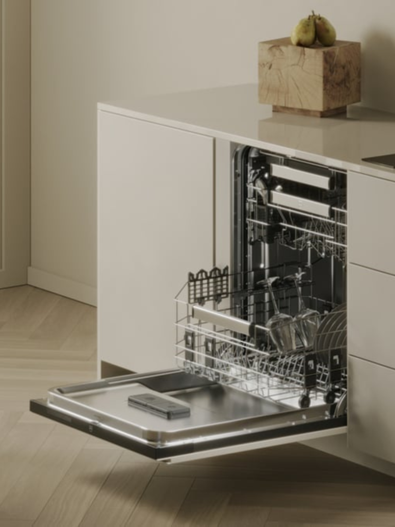Open integrated dishwasher with illuminated interior in a modern cream kitchen, displaying neatly arranged glassware and dishes on pull-out racks