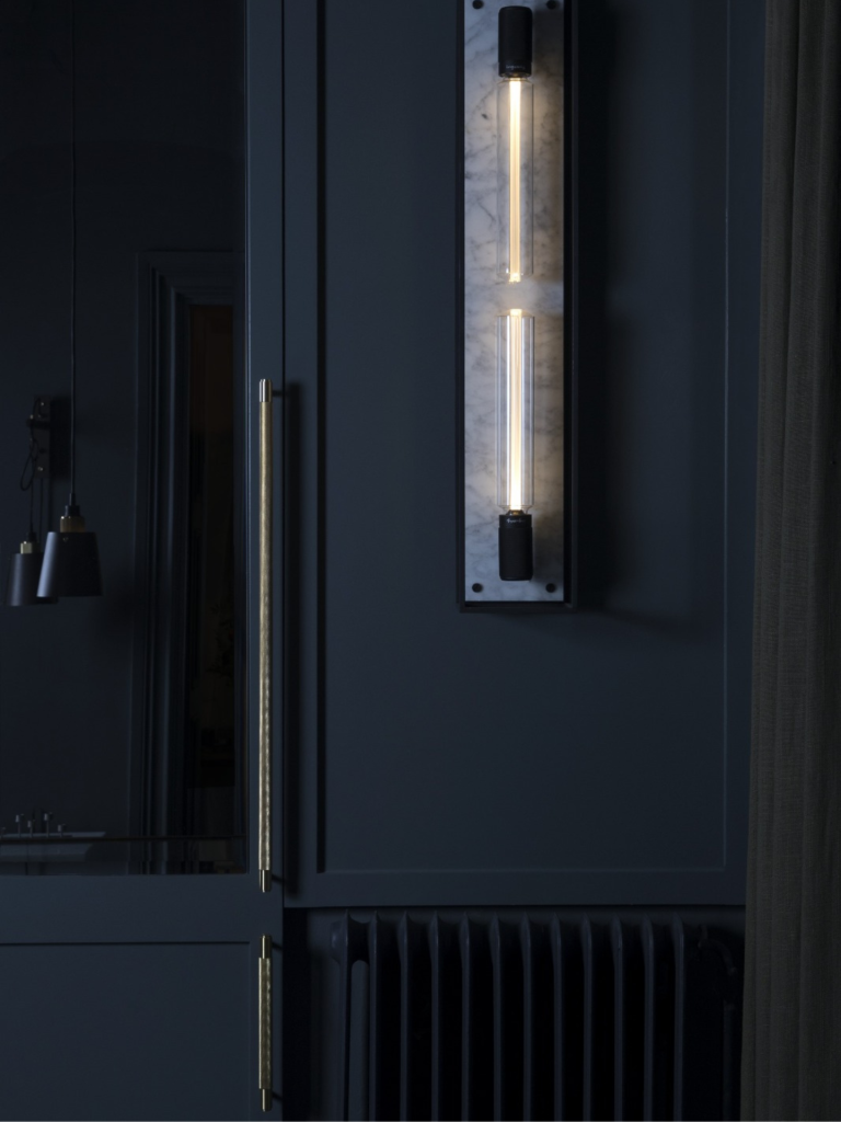 Modern dark kitchen with brass Buster + Punch handles and a vertical wall light set on a marble backplate
