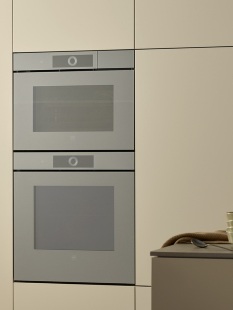 Minimalist built-in double oven with touch controls, integrated seamlessly into light-coloured cabinetry in a contemporary kitchen